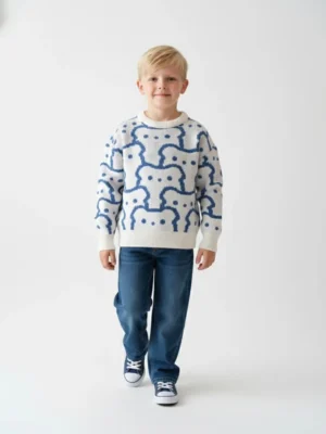 سويت شيرت أولادي شتوي كنزة محبوكة باللون الأبيض مائل للبيج. يتميز بنقوش زرقاء على شكل وجوه.