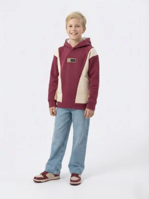 سويت شيرت أولادي شتوي بقبعة. تصميم Color-Block باللونين العنابي والكريمي على شكل V مع رقعة صغيرة.